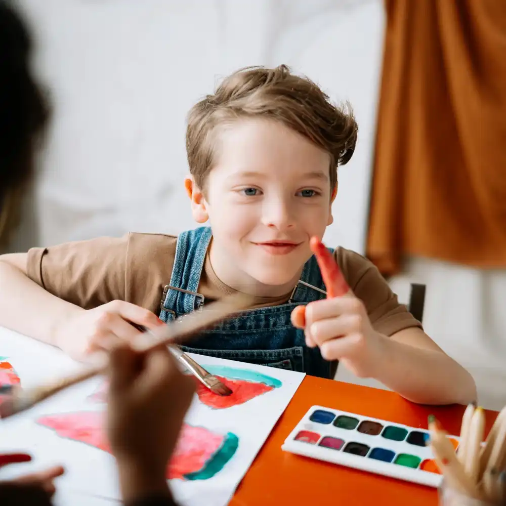 Young child painting during an art class, exploring creativity and colour mixing activities