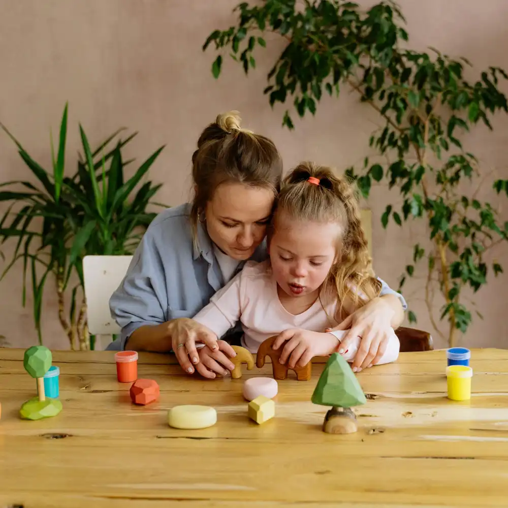 Teacher helping a young girl with Down syndrome during a supportive learning session using educational wooden toys.